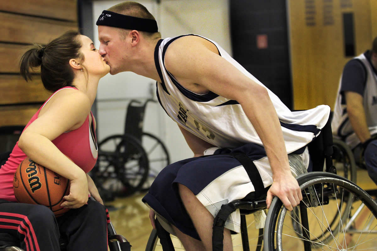 Kayla and Josh give each other a kiss during a wheelchair basketball charity game